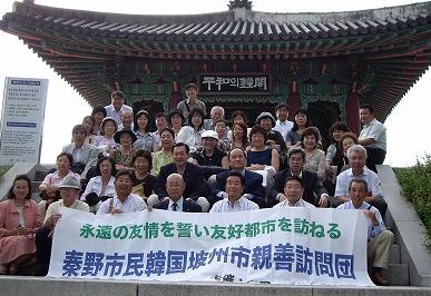 「永遠の友情を誓い友好都市を訪ねる 秦野市民韓国坡州市親善訪問団」と書かれた横断幕を掲げ、多数の団員と思われる男女が、屋根瓦が特徴的な「平和の鐘閣」の前で記念撮影している集合写真