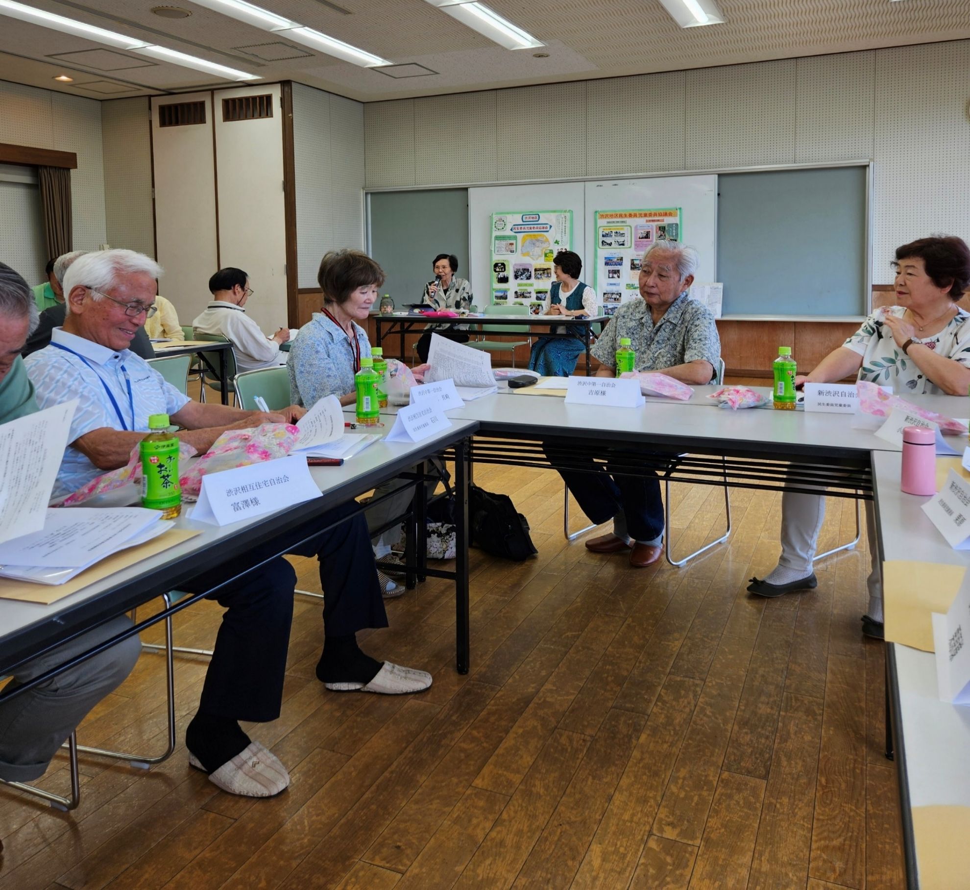 会議室で、少人数の大人が資料を見ながら意見を交わしている様子を写した懇談会の写真