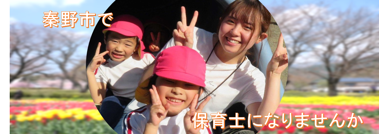 秦野市で保育士になりませんか（桜の木が立ち並ぶピンクや黄色のお花畑を背景に、丸枠の中に2人の園児と女性の保育士がピースサインをしている写真）