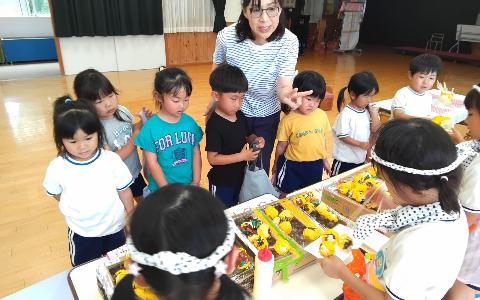 ハチマキをしている5歳児がお店屋さんになり、手作りのたこ焼きを焼いていて、お客さん役の4歳児が買いに来ている写真