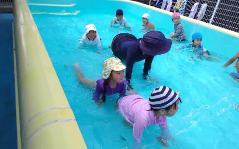 水着を着た4歳児がプールの中を四つん這いで歩いている写真