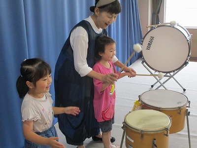 オルフの講師の指導のもと、2人の園児が太鼓などの打楽器を演奏している様子の写真