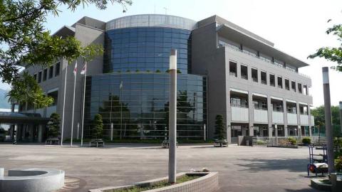 広大な前庭と旗竿が並ぶモダンなデザインの保健福祉センターの外観写真