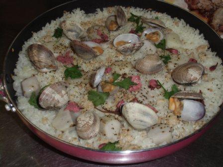 大きなフライパンに、たくさんの貝や具材がのった料理の写真