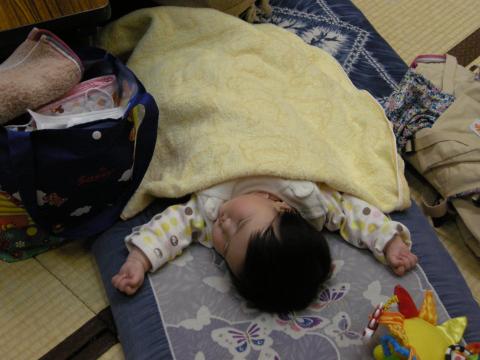 畳の上に敷かれた青いお昼寝マットの上で両手を広げて深く眠っている赤ちゃんの写真