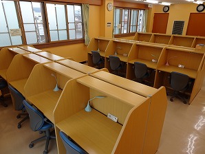 個人ブース型学習机が整然と並んでおり、それぞれの机に照明が備え付けられている学習室の写真