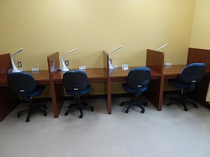 壁際に個人ブース型学習机が整然と並んでおり、それぞれの机に照明が備え付けられている学習室の写真