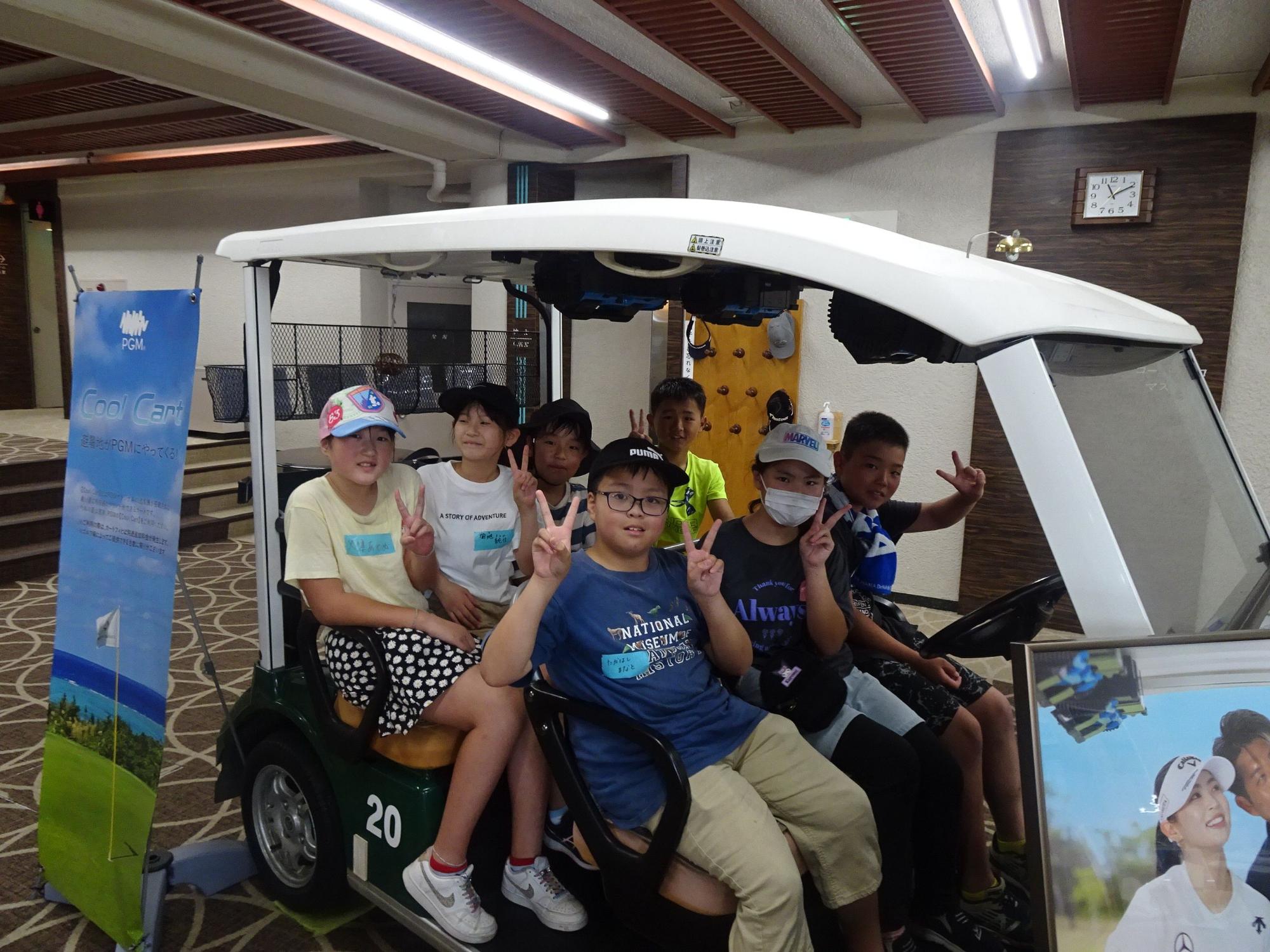 室内に展示されているゴルフカートに前後で乗り、それぞれがポーズをとっている子供達の写真
