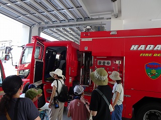 消防車が格納された車庫で、複数の親子連れが車内を覗き込んでいる写真