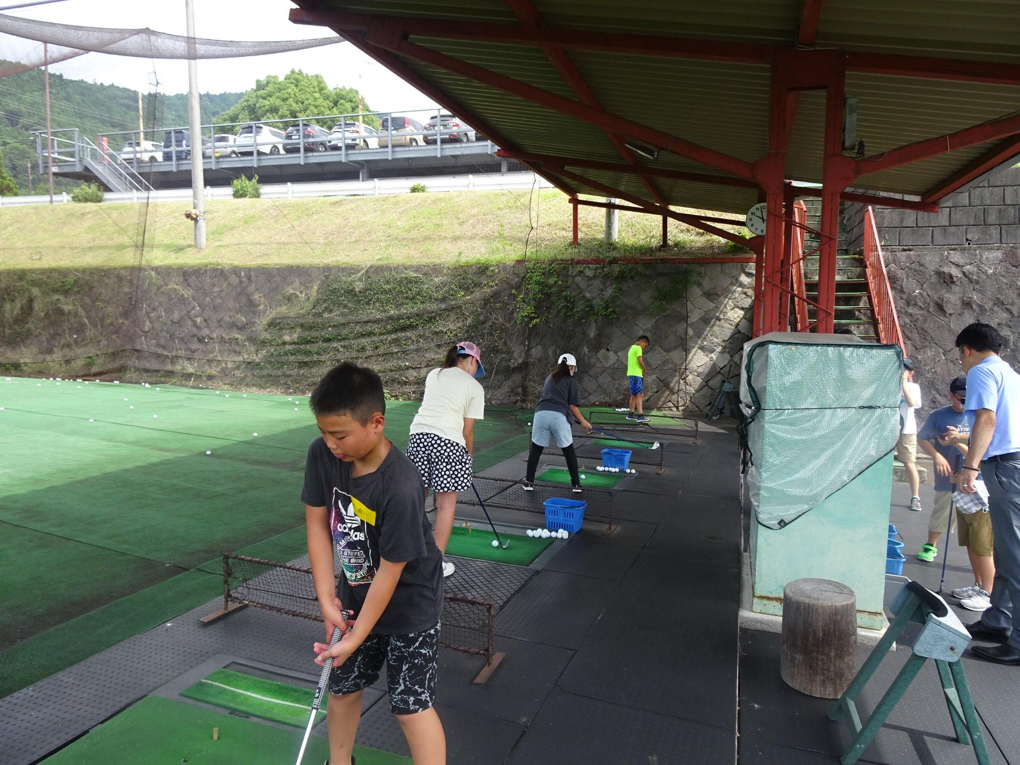 小学生の子供達が、クラブを握り打席に立って、打ちっぱなしの体験をしている写真