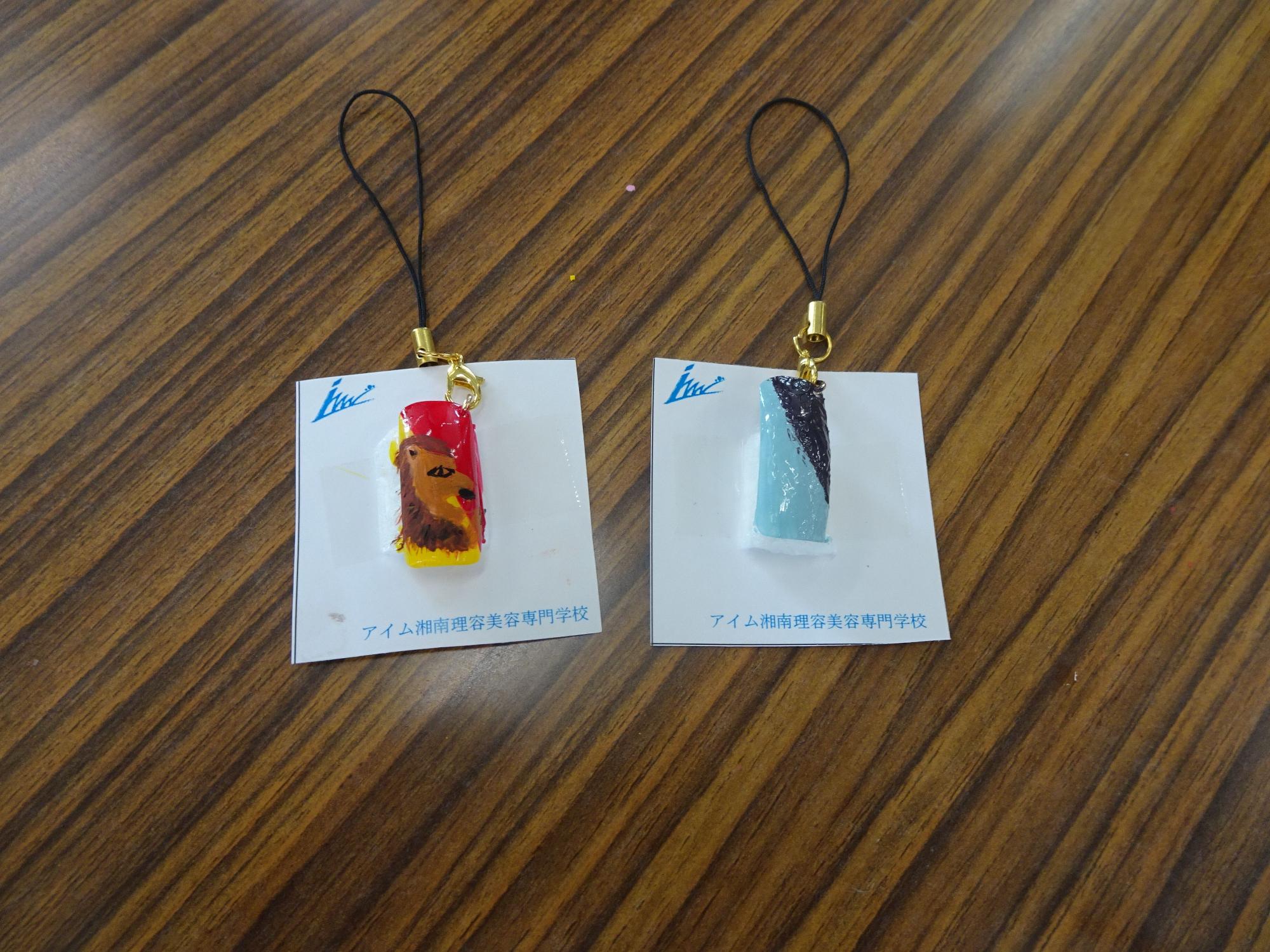 白い台紙の上に、色付けされた動物のイラストや水色とラメが組み合わさったネイルチップのストラップ写真