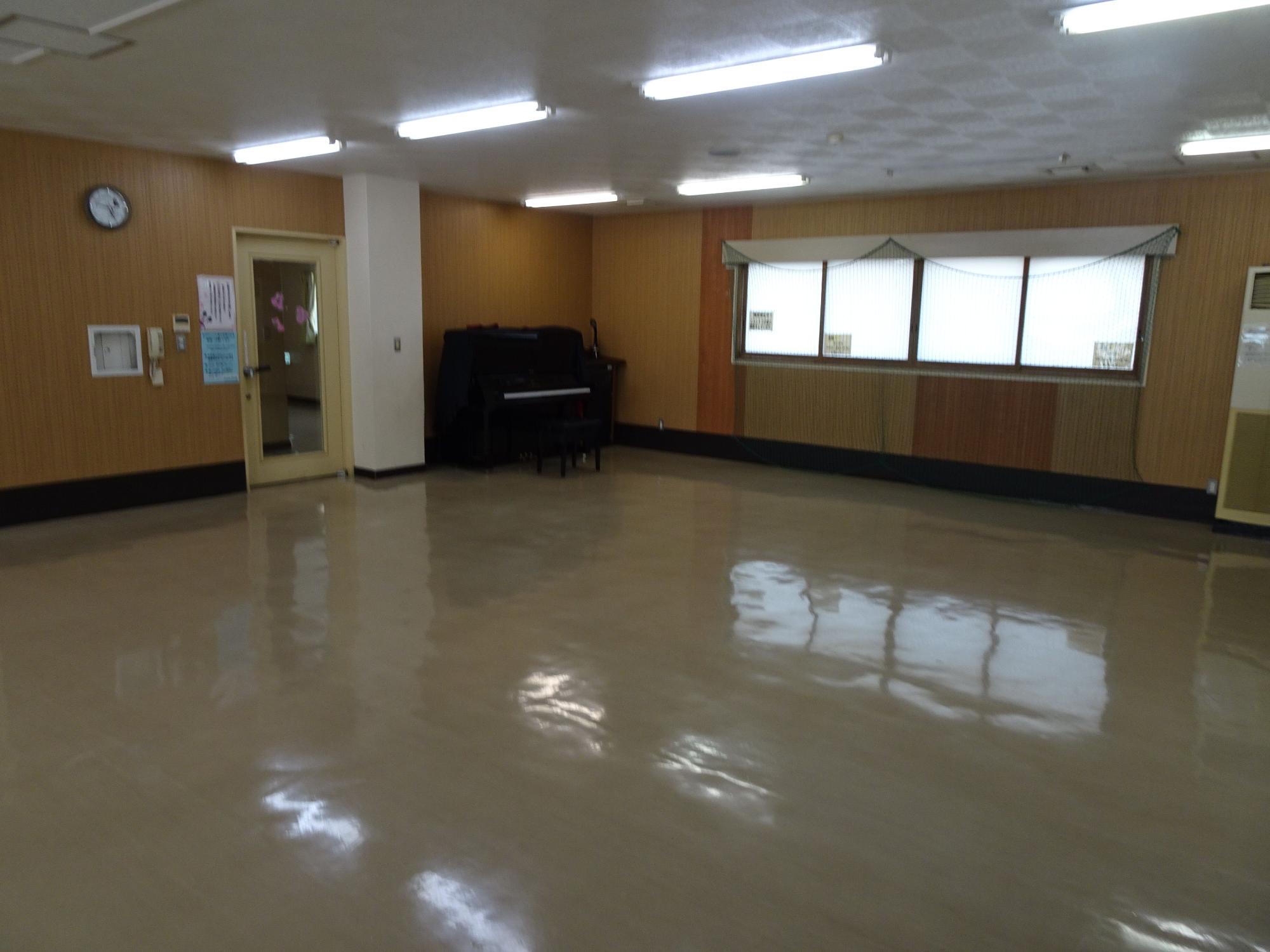 広い部屋の隅に黒のアップライトピアノが置かれた体験学習室の室内写真