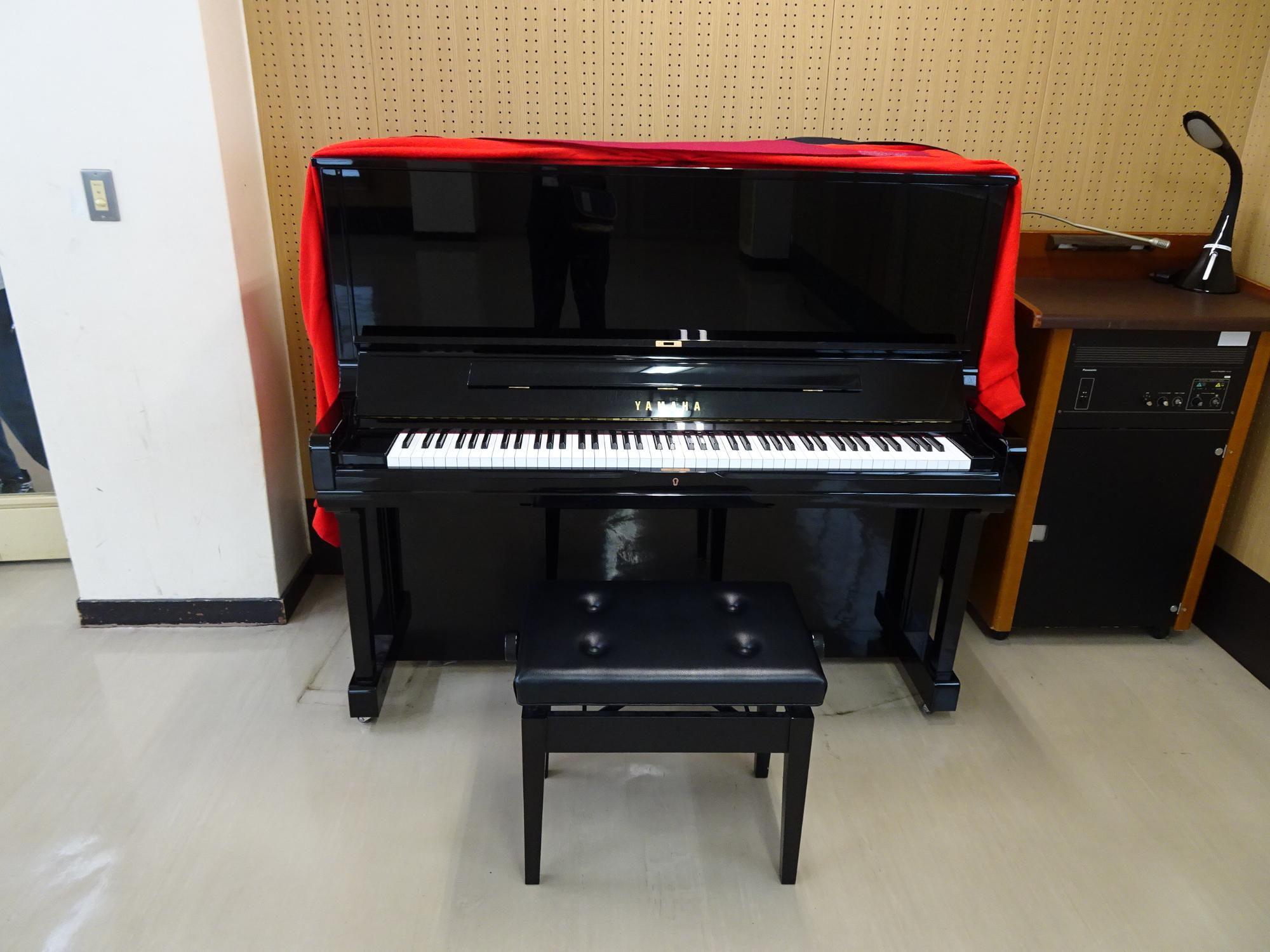 蓋を開けた黒のアップライトピアノを正面から写した写真