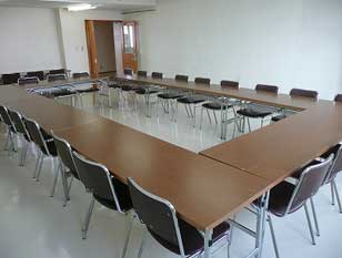 広い会議室にロの字型で机と椅子が配置された研修室の室内写真