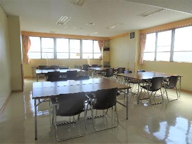 明るい日差しが差し込む部屋に、4人掛けの机と椅子が複数並べられた高校生学習室の室内写真