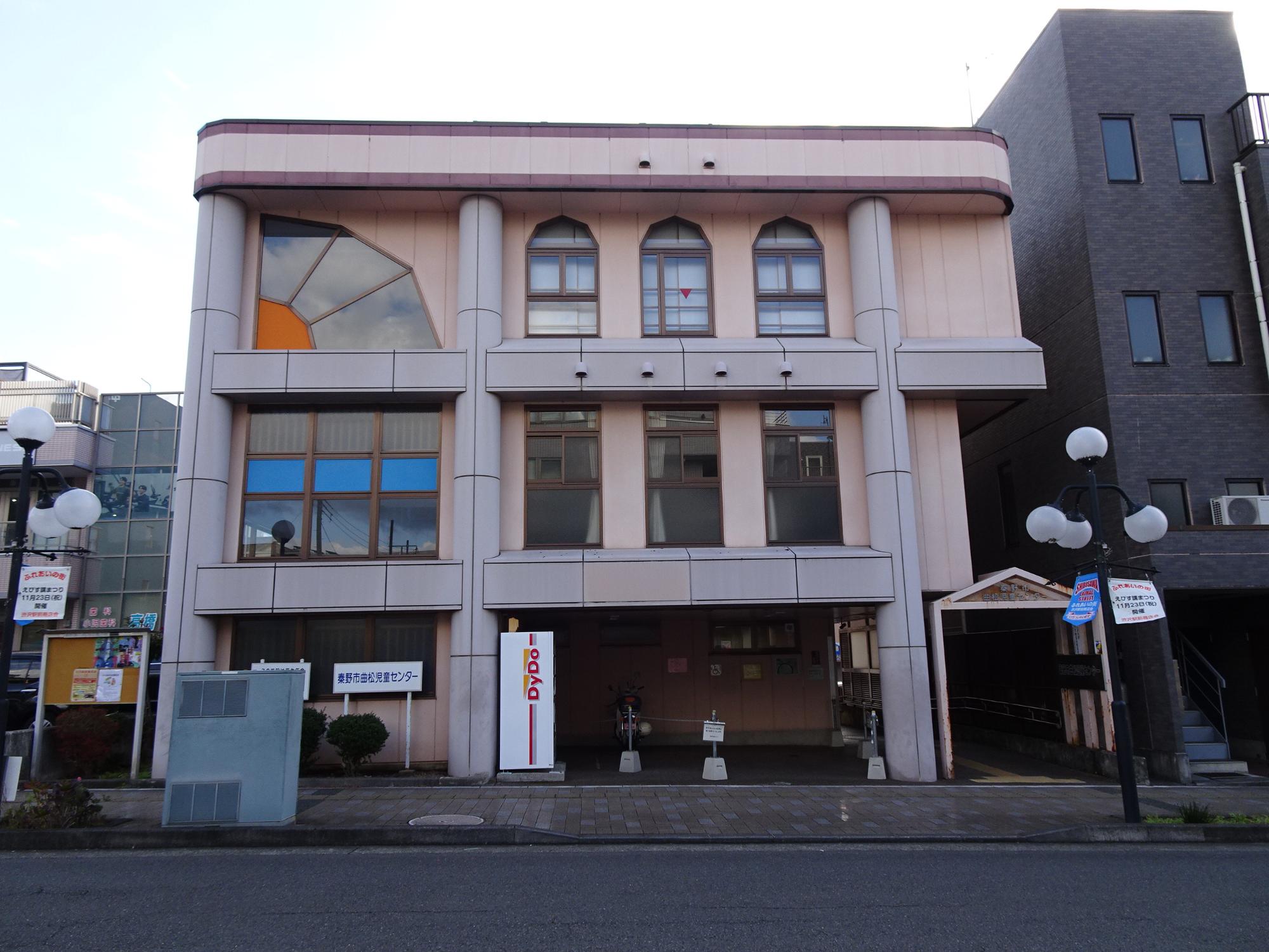 三階建てのクリーム色の壁を持つ曲松児童センター外観写真