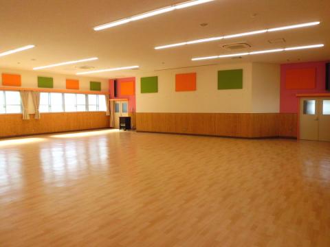 オレンジ色と黄緑色の四角が並んだ壁の多目的ホールの写真