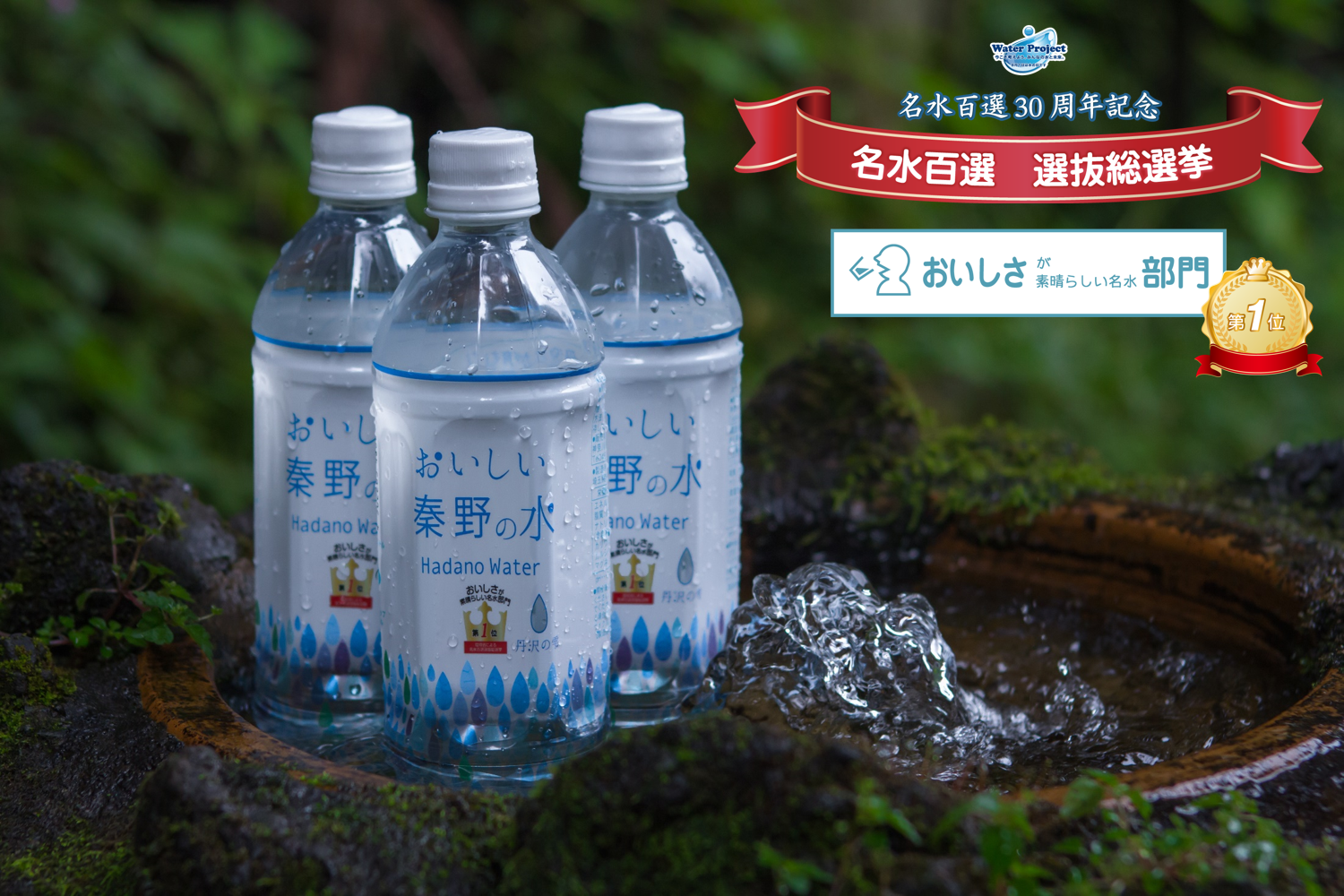 右上に「名水百選30周年記念」「名水百選 選抜総選挙」と「おいしさが素晴らしい名水部門 第1位」の文字が書かれ、濃い緑の苔に覆われた湧水石の周りに、水滴のついた3本の「おいしい秦野の水 Hadano Water」のペットボトルが置かれた広告用の写真