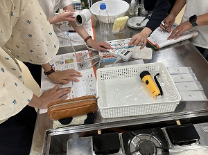 調理実習室で参加者が資料や調理道具を使いながら作業を進めている様子を写した、指導者養成講座の写真