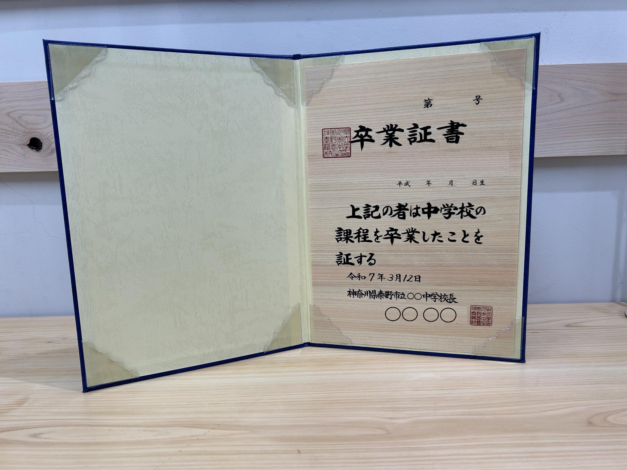 濃紺の表紙を開いた状態の木の紙卒業証書の写真