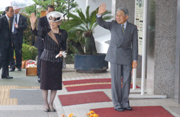 天皇皇后両陛下が並んで立たれ、笑顔で手を振って人々に挨拶されている様子の写真