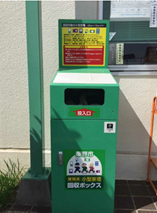 環境資源センターの屋外に設置された、明るい緑色の直方体で、上部の黄色いプレートに小型家電の回収品目と注意書きが表示され、中央に投入口があり、下部に「使用済 小型家電 回収ボックス」という文字と丹沢はだの三兄弟のキャラクターのイラストが描かれた小型家電回収ボックスの写真