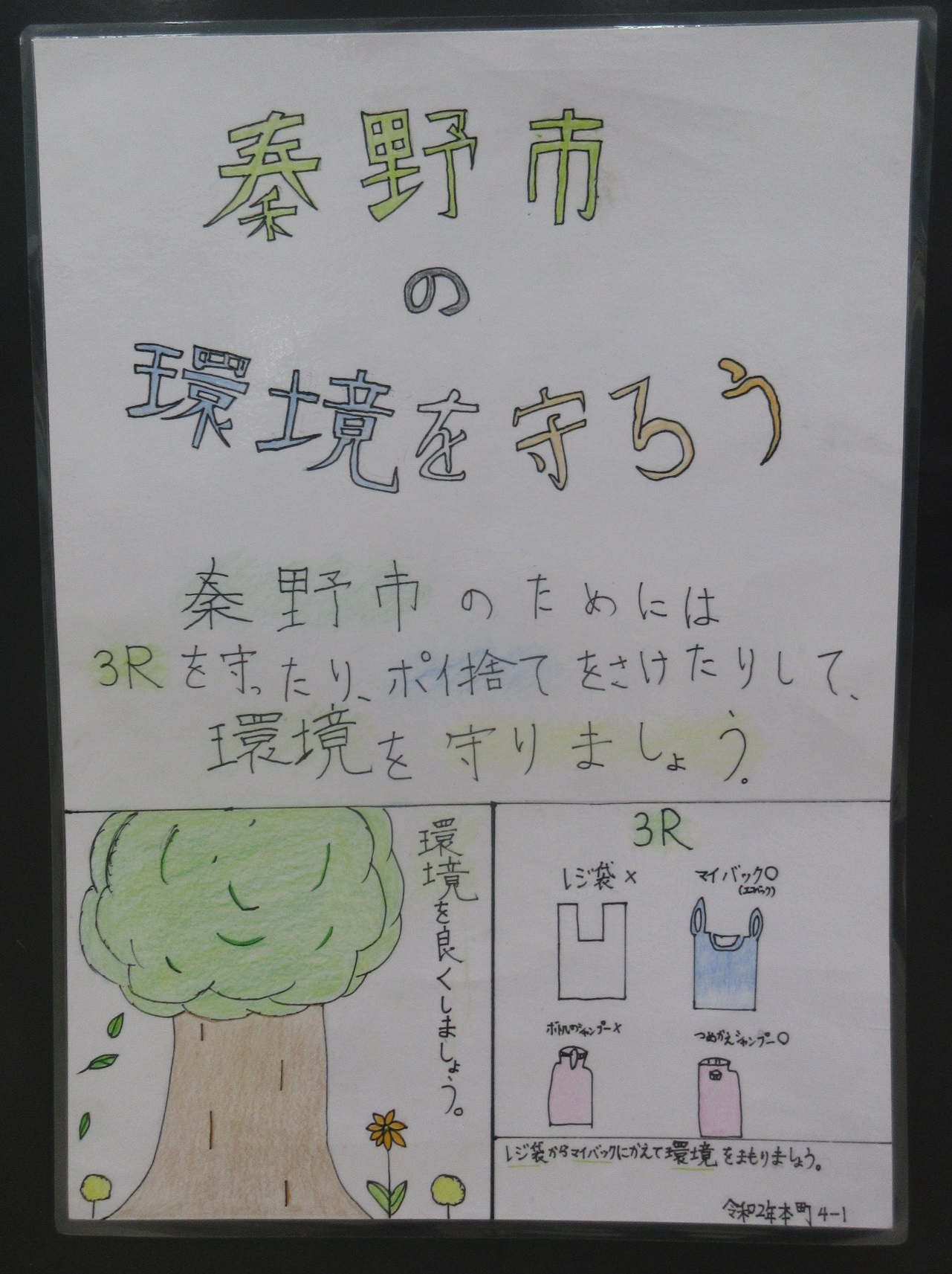 「秦野市 の 環境を守ろう」というタイトルと、「秦野市のためには3Rを守ったり、ポイ捨てをさけたりして、環境を守りましょう」と書かれ、下部には大きな木のイラストと共に3Rの一つとしてマイバッグの使用が推奨されている環境啓発ポスター画像
