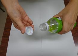 緑色のペットボトルのキャップを、両手を使って開けている様子を写した写真