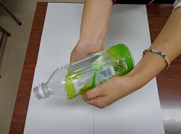 両手で、ペットボトルに巻かれた緑色のラベルを、剥がしている様子を写した写真