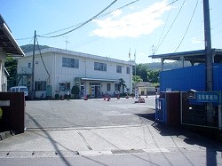 奥に2階建ての白い建物が見える、入り口の門から撮影した環境資源センター敷地内の写真