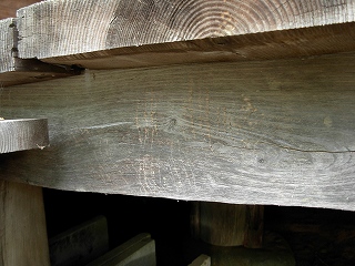 経年劣化した木製の太い梁に、いくつもの小さな動物の足跡のような引っかき傷が残されている様子を捉えた写真