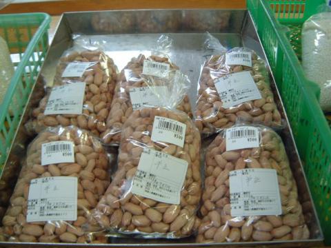 四角い銀色のトレイに、ラベルが貼られ、500円と書かれた値札が付いた殻付き落花生が、透明なビニール袋に小分けされて山積みに陳列されている写真