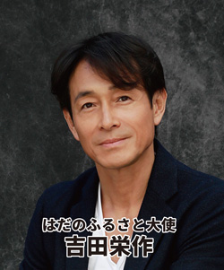 ふるさと大使を務める俳優の吉田栄作が、濃い色のジャケットと白いシャツを着て、やや微笑んだ表情で正面を見つめるバストアップのポートレート写真