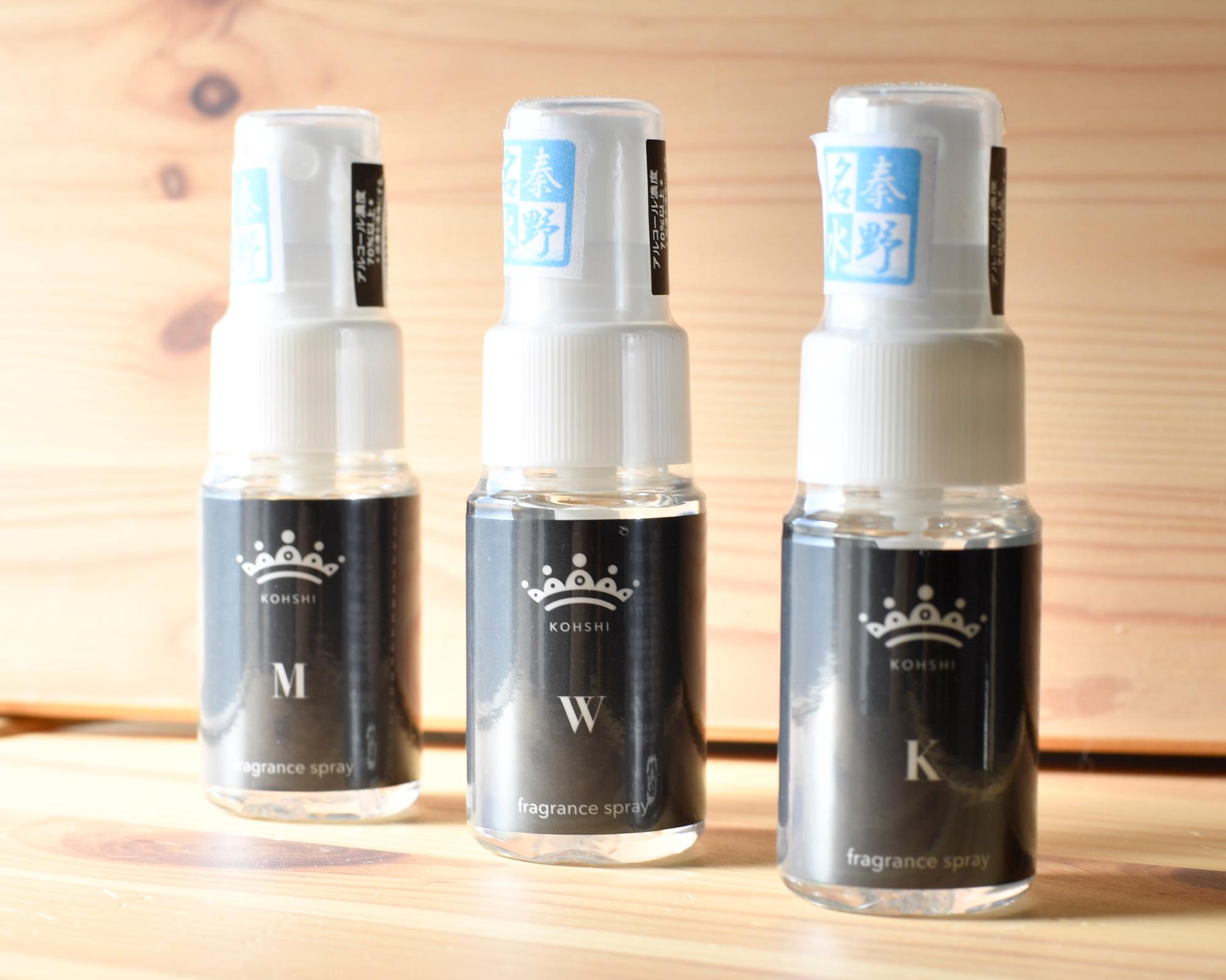 木目のテーブルの上に、黒いラベルに白い王冠のロゴと「KOHSHI」「M」「W」「K」の文字が印刷された3本の小型フレグランススプレーボトルが並ぶ商品写真