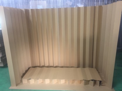 クリーム色と茶色の縦縞模様の段ボール製パーティションが、緑色の床の上に設置されている室内の写真