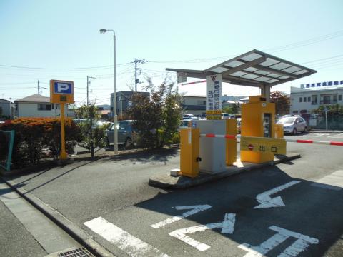 黄色い機械が並び、その上には太陽光パネルのような屋根があり、赤と白のバーが下りた状態の渋沢駅北口駐車場写真