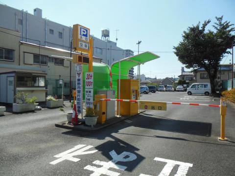 黄色と緑色の無人精算機と料金看板、進入禁止を示す黄色と赤色のバーがある片町駐車場写真