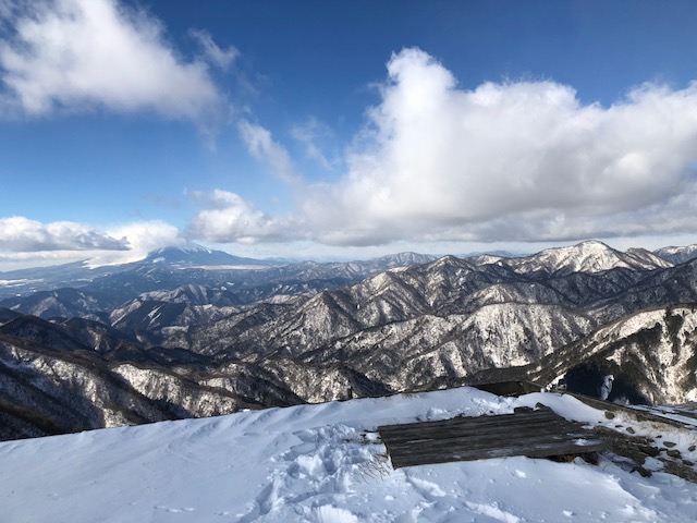 雪が積もった山頂から、眼下の雪を頂いた山々を撮影した塔ノ岳の写真