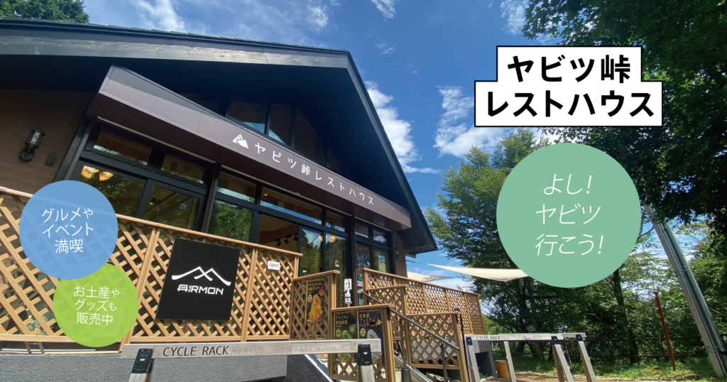 青空のもと、ヤビツ峠レストハウスの外観を背景に、「グルメやイベント満喫」「お土産やグッズも販売中」「よし！ヤビツ行こう！」といった魅力的なテキストが配置された画像