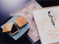 化粧箱に詰められたお菓子と、その横のお皿に盛りつけられたモナカのようなお菓子が並べて置かれている写真