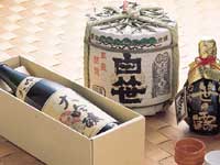 化粧箱に入っている「大吟醸」と書かれたラベルが貼られたお酒の瓶、「白笹」と書かれ酒樽と黒い瓶のお酒が並べて置かれている写真