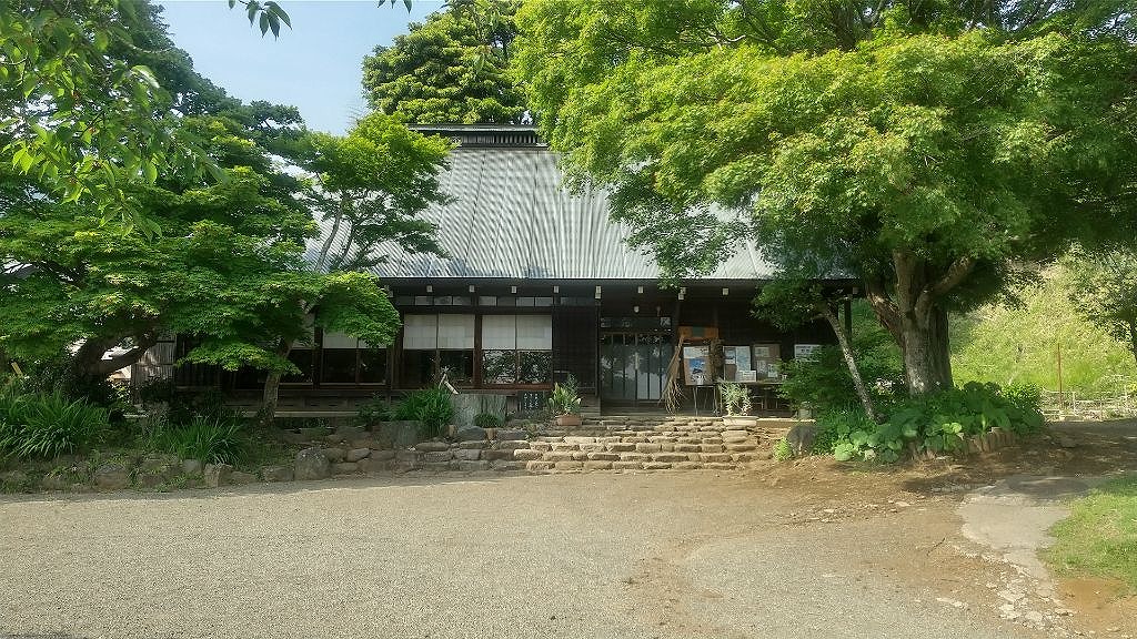 緑豊かな木々に囲まれた日本家屋風の建物を正面から捉えた写真で、正面には石造りの階段が数段設けられており、手前には広々とした砂利敷きの庭が広がっている緑水庵の外観写真