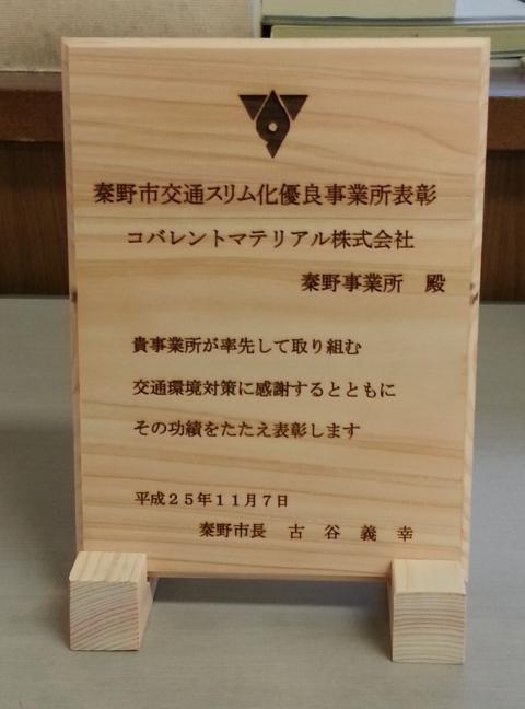 木製の台座に乗せられた表彰状で、秦野市交通スリム化優良事業所表彰としてコバレントマテリアル株式会社秦野事業所が表彰されたことが記されている記念品写真
