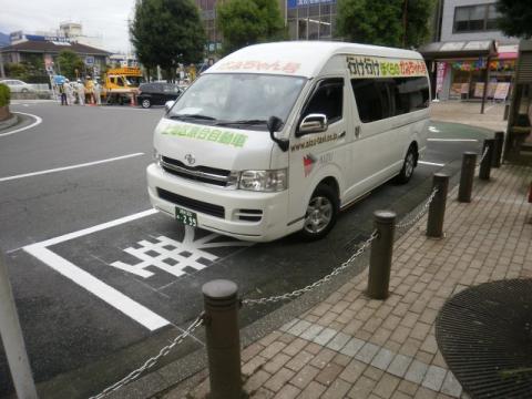 道路脇の駐車スペースに白いワンボックスカーが停車し、フロントガラスに「移住お試し住宅」と書かれた行け行けぼくらのかみちゃん号の写真