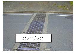 「グレーチング」の文字と排水溝の蓋として使われている細長い金属製のグレーチングの写真