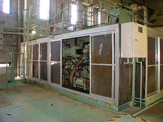 施設の広々としたコンクリート床の空間に設置された、大型のベルトプレス脱水機の写真