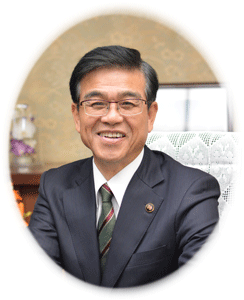 濃紺のスーツとネクタイを着用し、メガネをかけた高橋市長が、書斎のような室内で明るい笑顔を浮かべながら正面を向いている上半身の顔写真