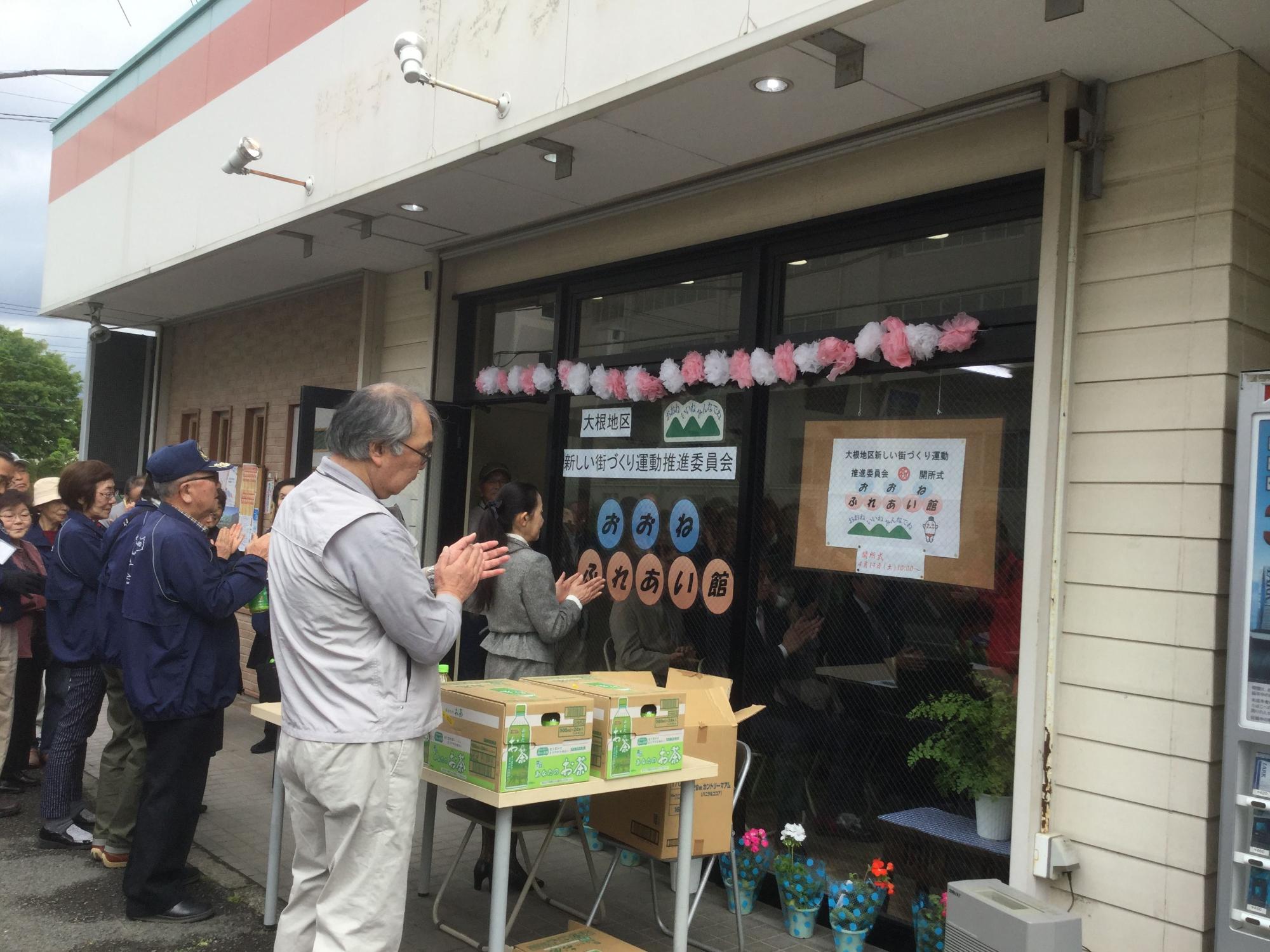 新しく開所されたおおねふれあい館の前で、集まった人々が手を合わせ祈願している写真