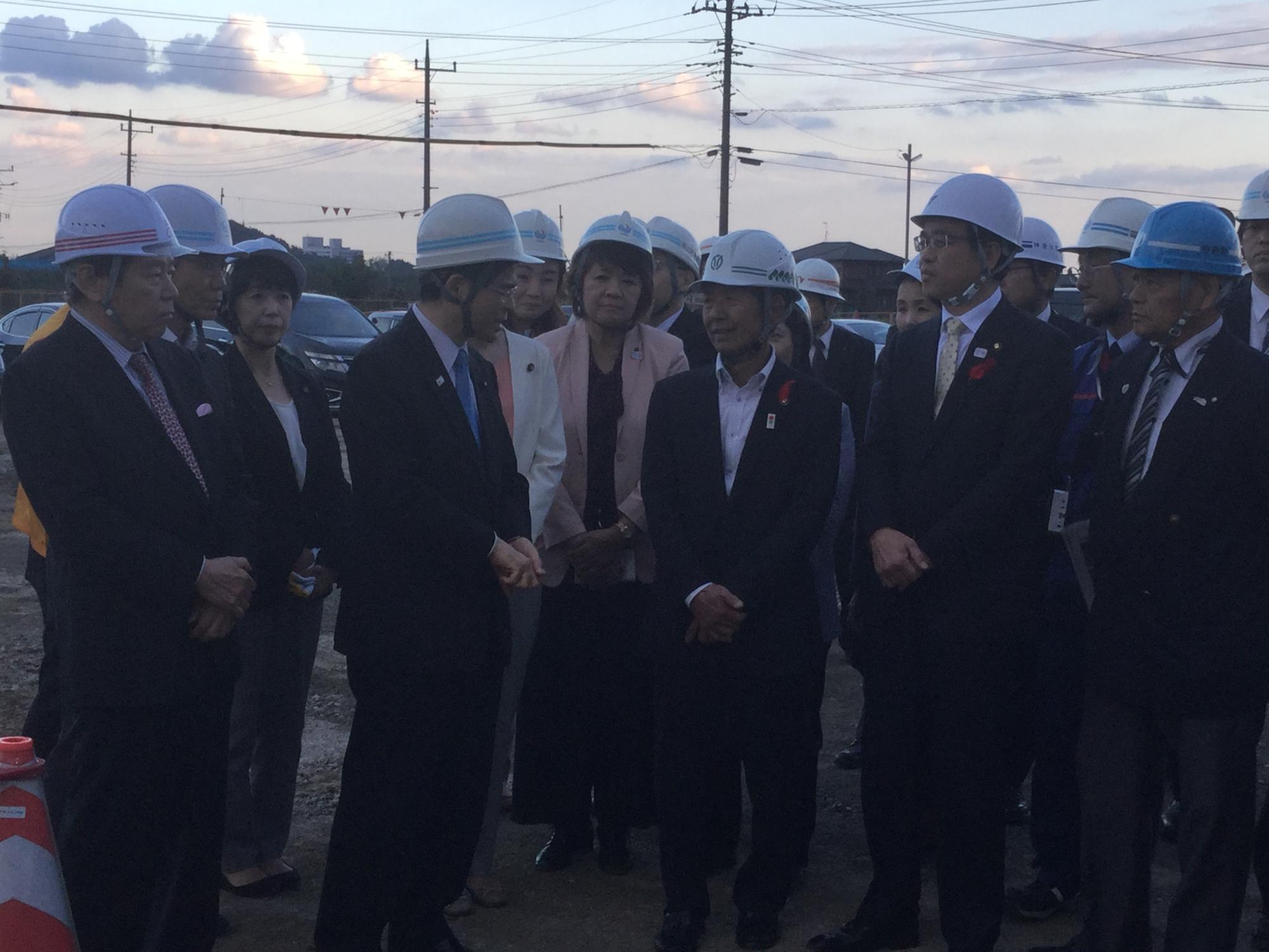 ヘルメットを被った複数の関係者を囲み、高橋市長と石井国土交通大臣が話をしている写真