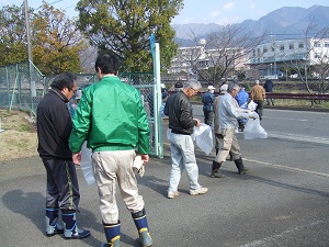 清掃活動とみられる作業で、緑色のジャンパーを着た男性や胴長靴を履いた男性など数人が、それぞれ白いビニール袋を持って道路沿いを歩いている姿を写した写真